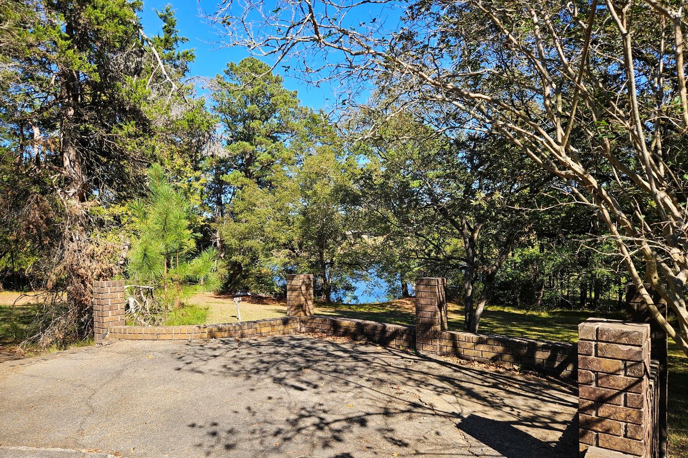 Paved court bordered by brick walls and piers, with the lake visible beyond the brick piers